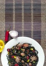 Spaghetti black with seafood and vegetables on a white plate multi-colored background top view vertical Royalty Free Stock Photo