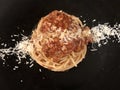 Spaghetti Bolognese with cheese . Black background .