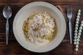 Spaghetti carbonara, a delicious mix of ham, bacon and hot cheese, served in a white plate on a ready to eat wooden table. Royalty Free Stock Photo