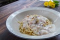 Spaghetti carbonara, a delicious mix of ham, bacon and hot cheese, served in a white plate on a ready to eat wooden table. Royalty Free Stock Photo