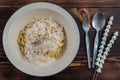 Spaghetti carbonara, a delicious mix of ham, bacon and hot cheese, served in a white plate on a ready to eat wooden table. Royalty Free Stock Photo
