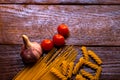 Spaghetti, cherry tomatoes and garlic on a wooden board