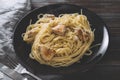 Spaghetti with chicken fillet on a black plate on a dark wooden , napkin, fork, pasta