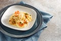Spaghetti dish with shrimps, parsley and garlic on a plate, Mediterranean seafood, blue napkin and rustic gray background with Royalty Free Stock Photo