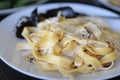 Spaghetti and fettuccine with ingredients for cooking pasta on wooden table with blank of round wooden kitchen board Royalty Free Stock Photo