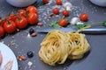 Spaghetti and fettuccine with ingredients for cooking pasta on wooden table with blank of round wooden kitchen board Royalty Free Stock Photo
