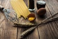 Spaghetti and flour and eggs with kitchenware on wooden background Royalty Free Stock Photo