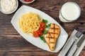 Spaghetti and grilled chicken on a white porcelain plate with buttermilk and sauces on wooden table