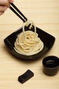 Spaghetti macaroni in black ceramic plate with chopsticks at bamboo mat