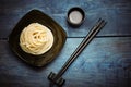 Spaghetti macaroni in black plate with chopsticks at wooden table Royalty Free Stock Photo