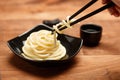 Spaghetti macaroni in black plate with chopsticks at wooden table Royalty Free Stock Photo