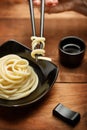 Spaghetti macaroni in black plate with chopsticks at wooden table Royalty Free Stock Photo