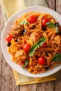 Spaghetti with meat balls, vegetables in a tomato sauce close-up on a plate on a table. Vertical top view, rustic Royalty Free Stock Photo