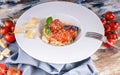 Spaghetti and meatballs in tomato sauce on a white plate, cherry tomatoes on a wooden table