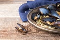 Spaghetti with mussels, tomatoes in spicy sauce in the original plate on the old wooden table. Clams Mytilus closeup. Royalty Free Stock Photo