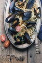 Spaghetti with mussels, tomatoes in spicy sauce in the original plate on the old wooden table. Clams Mytilus closeup. Royalty Free Stock Photo