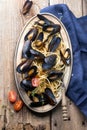 Spaghetti with mussels, tomatoes in spicy sauce in the original plate on the old wooden table. Clams Mytilus closeup. Royalty Free Stock Photo