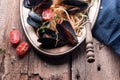 Spaghetti with mussels, tomatoes in spicy sauce in the original plate on the old wooden table. Clams Mytilus closeup. Royalty Free Stock Photo