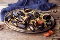 Spaghetti with mussels, tomatoes in spicy sauce in the original plate on the old wooden table. Clams Mytilus closeup. Royalty Free Stock Photo