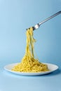 Spaghetti pasta with a fork on a white plate on a blue background. Creative, minimal concept Royalty Free Stock Photo