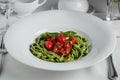 Spaghetti pasta with homemade spinach sauce, green spaghetti, fried tomatoes and fresh basil leaves, vegetarian foodclose-up