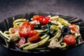 Spaghetti pasta with olive oil, tomatoes, herbs, chilly, and cut chicken breast. Italian cuisine. Plate with food on a black table Royalty Free Stock Photo