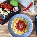 Spaghetti with red sweet pepper and sesame sauce lie on a blue plate on a wooden table Royalty Free Stock Photo