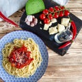 Spaghetti with red sweet pepper and sesame sauce lie on a blue plate on a wooden table Royalty Free Stock Photo