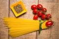 Spaghetti and Roma tomatoes isolated on wood table background. Uncooked Italian dried spaghetti. Top view.