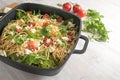 Spaghetti salad with tomatoes, arugula, mozzarella cheese and olives in a large black bowl, cold Mediterranean party meal on a