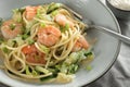 Spaghetti with shrimps, zucchini and spring onions in a grey plate with a fork, close up shot of a healthy Mediterranean meal