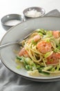 Spaghetti , shrimps, zucchini and spring onions, a healthy Mediterranean meal  in a grey plate with a fork, napkin and spice bowls Royalty Free Stock Photo