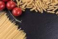 Spaghetti, spirelli and cherry tomatoes on black slate plate Royalty Free Stock Photo