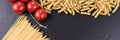 Spaghetti, spirelli and cherry tomatoes on black slate plate Royalty Free Stock Photo