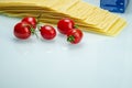 Tomatoes with lasagna on white reflexive glass