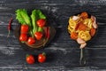 Spaghetti with tomato and ham served on a small cast-iron frying pan, rustic background. Tomatoes and leaves of lettuce