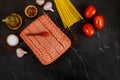 Spaghetti, tomato, olive oil, garlic, ground beef on black background