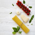 Spaghetti, tomatoes, basil, parmesan, garlic. Ingredients for cooking italian pasta on a white wooden background, flat lay. From a Royalty Free Stock Photo