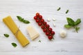 Spaghetti, tomatoes with basil, parmesan, garlic. Ingredients for cooking pasta on a white wooden background, flat lay. Royalty Free Stock Photo