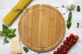 Spaghetti, tomatoes, basil, parmesan, garlic. Round board in the center. Ingredients for cooking pasta on a white wooden table, fl Royalty Free Stock Photo