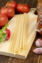 Spaghetti, tomatoes, garlic, peppers and herbs over wood table Royalty Free Stock Photo
