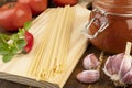 Spaghetti, tomatoes, garlic, peppers and herbs over wood table Royalty Free Stock Photo