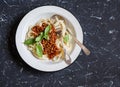 Spaghetti with vegetarian lentil bolognese on a dark background.