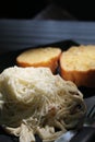 Spaghetti with white sauce, ham and mushrooms topped with cheese and garlic bread served on a black plate. Royalty Free Stock Photo