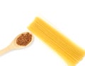 Spaghetti on a white table and buckwheat on a wooden spatula.