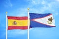 Spain and American Samoa two flags on flagpoles and blue cloudy sky