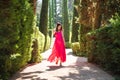 Pretty girl in red dress walking in green park