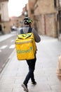 Spain, Salamanca - April 3, 2022: Food and grocery delivery. The bicycle courier, with a yellow thermo backpack, the