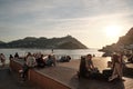 Groups of people enjoy chatting at sunset with La Concha Bay in the background