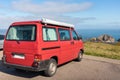 Spain; Sep 2020: Vintage red van parked in front of the ocean. Campervan with canopy prepared to sleep inside, no logos. Low cost Royalty Free Stock Photo